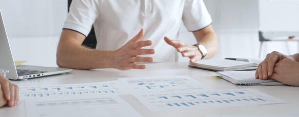 Professional team reviewing financial charts, collaborating intently around conference table in contemporary workspace, sharing insights during strategic planning session