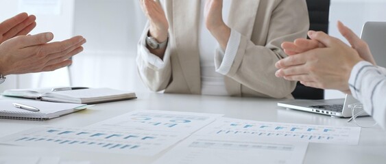 Professional business team clapping hands, celebrating successful presentation, displaying collaborative spirit and workplace enthusiasm in modern office setting