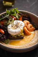 Bowl with hummus, poached egg, shrimp and fresh vegetable salad