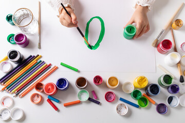 Child drawing with various art materials for creative and sensory development. Toddler activity with colorful gouache.