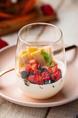 Glass dessert with berries, vanilla cream and waffles served on wooden table