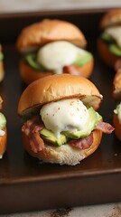 Delicious breakfast sliders with avocado, bacon, and poached egg on a baking sheet
