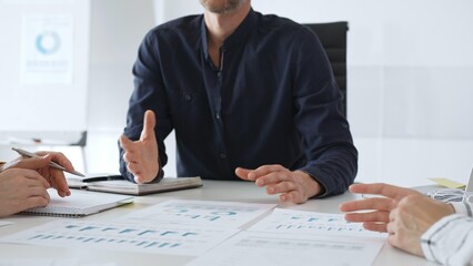 Business people team analyzing financial data and discussing growth strategy during meeting, pointing at charts and graphs, taking notes in modern office