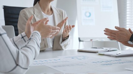 Professional business team clapping hands, celebrating successful presentation, displaying collaborative spirit and workplace enthusiasm in modern office setting