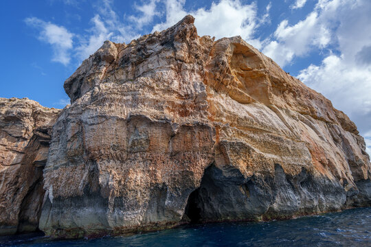 Sunlit Coastal Cliff with Sea Caves over Deep Blue Mediterranean