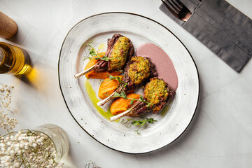 Three baked lamb chops with herb crust, served with vegetables and sauce