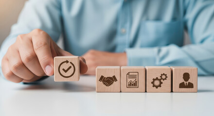 Hand arranging wooden blocks with business icons representing workflow success