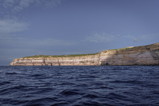 Sheer Limestone Sea Cliffs under Clear Evening Sky and Dark Waves