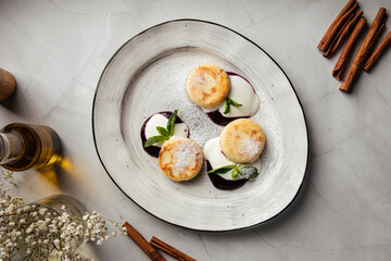 Delicious cottage cheese pancakes served with sour cream, fresh mint, and berry sauce on a white plate