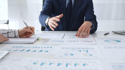 Business professionals discussing financial reports and marketing charts during corporate meeting, focusing on strategy, planning, data analysis, and teamwork