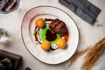 Tender grilled beef filet with crispy potato croquettes and green pea puree, served with demi-glace sauce