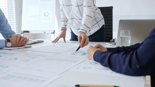 Business team analyzing financial charts during strategy meeting, professionals discussing data and performance metrics at workplace for decision making success