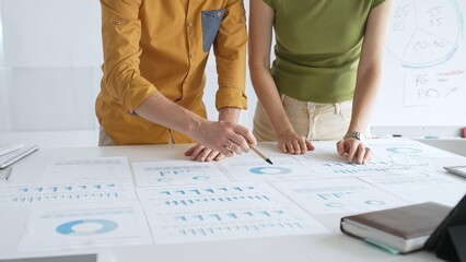 Business professionals analyzing financial reports, pointing at charts during collaborative meeting, discussing data with focused professional demeanor