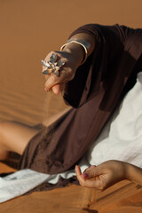 there's a beautiful ring on her hand, and yellow desert sand is falling