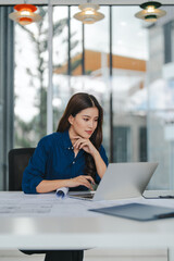 Fototapeta premium Asian woman engineer reviews blueprints in an office for design projects