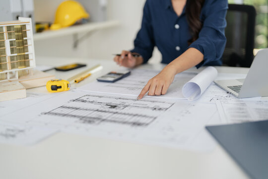 Asian woman architect designs projects with blueprints in an office