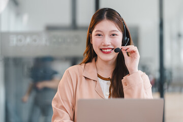 Young woman headset smiling at laptop offering friendly customer support in modern office, cheerful and professional