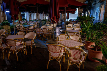 Nighttime Outdoor Cafe with Wicker Bistro Chairs and Maroon Umbrellas