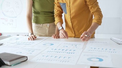 Professional team analyzing financial charts, collaborating intently around conference table in sleek, contemporary workspace. Business people concept