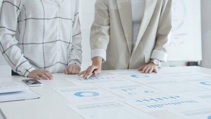 Professional women analyzing financial charts, discussing business strategy in modern light office, in collaborative corporate environment. Business people concept