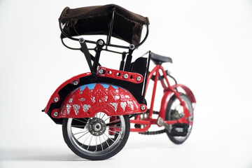 A detailed miniature model of a red becak, a traditional Indonesian rickshaw. This image is perfect for concepts of Indonesian culture, travel, handmade crafts, or vintage transportation.