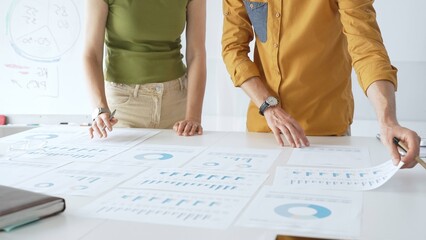 Professional team analyzing financial charts, collaborating intently around conference table in sleek, contemporary workspace. Business people concept