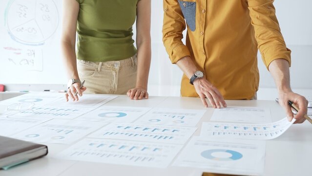 Professional team analyzing financial charts, collaborating intently around conference table in sleek, contemporary workspace. Business people concept