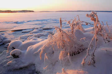 A view of a frozen lake illuminated by the setting sun on a winter evening