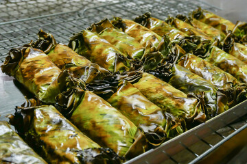 Leaf wrapped grilled dumplings on a metal rack.