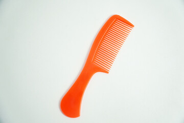 A bright orange plastic comb is isolated on a clean white background. Its vibrant color and simple design make it perfect for concepts of hair care, beauty, or grooming accessories.

