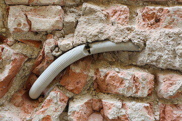 Gaine de conduit de fil électrique dans un mur de brique © luzulee