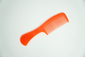 A bright orange plastic comb is isolated on a clean white background. Its vibrant color and simple design make it perfect for concepts of hair care, beauty, or grooming accessories.

