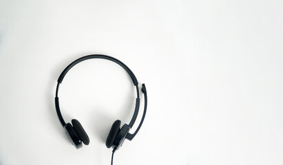 A pair of black on-ear headphones with a microphone boom, viewed from the top down on a white background. This image is perfect for concepts of a call center, customer service, communication, or music