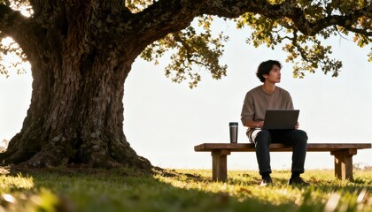 Fototapeta premium Man Working on Laptop Under a Large Tree