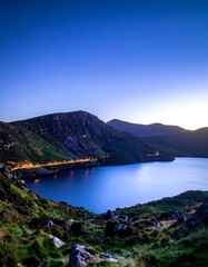 Fototapeta premium Evening landscape lake, mountain, grass, and twilight