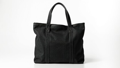 Naklejka premium Black eco tote bag lies on white backdrop. Blank shopping bag with short handles for merchandise. Fashionable textile handbag for customer carrying stuff. Reusable canvas accessory for retail sale.