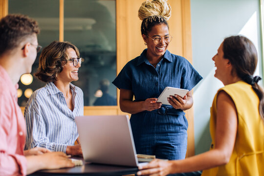 Diverse coworkers discuss ideas at a meeting with laptops and tablets