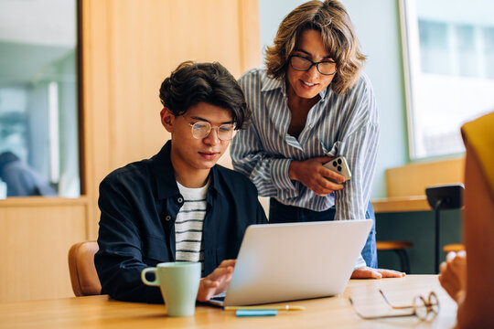 Fototapeta Young man and woman collaborating on a laptop at a desk