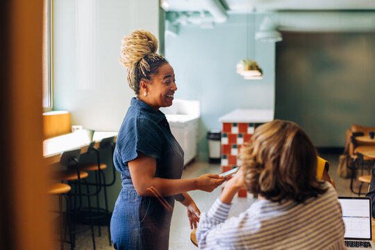 Smiling woman speaking to a seated colleague in a casual office environment