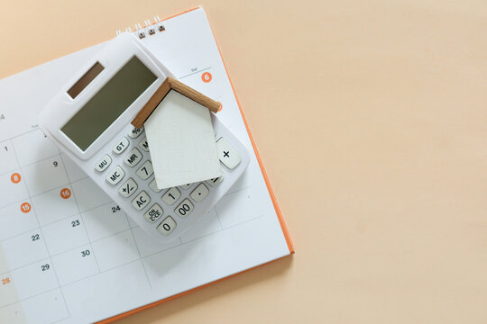 close up top view group of home model , calculator and calendar on beige  color background with space for money management ,home loan and personal financial concept