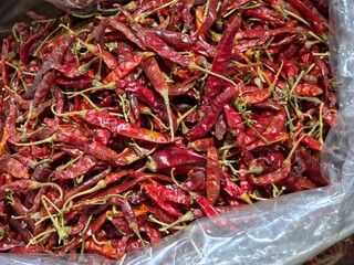 a large, dense pile of dried red chili peppers, likely contained within a clear plastic bag 