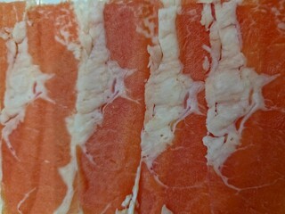 Close up of several very thinly sliced pieces of raw beef chuck