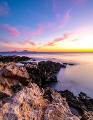 Obraz premium Vibrant coastal scene features rock formations, ocean, and colorful sunset