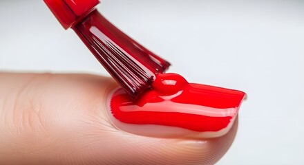 A nail polish brush painting a fingernail, sharp macro capture, with a soft white backdrop.