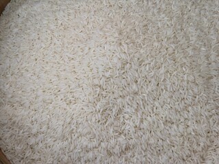 Close-up, high-angle, full-frame shot of uncooked long-grain Jasmine rice, showing slender, elongated, slightly translucent white kernels.