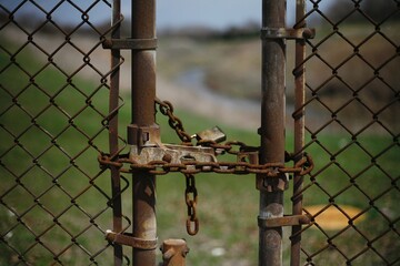 Rusted Lock and Chain Restricting Entrance to Grassed Area with River  
