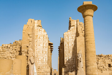 Central corridor of the temple of Karnak, Luxor, Egypt, with two statues of the pharaoh Ramses one in front of each other. Blue sky on the background.
