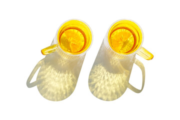 Top view two yellow color Glasses of Drinking natural water with slises of orange fruit isolated on white background, sun shadow and sunlight reflection, Summer drink in bright colored glass cups