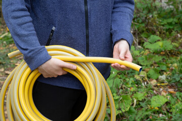 A water hose in a person's hands near a house.