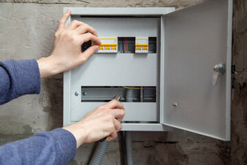 An electrician is installing wires on an electric meter
